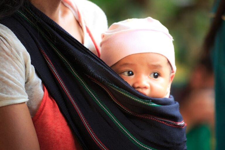 Parent babywearing a baby in a soft carrier outdoors