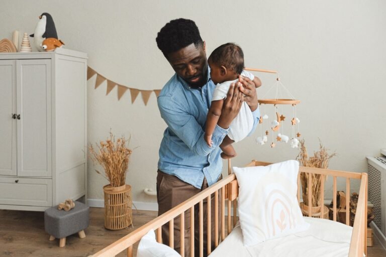 Parent placing baby in a crib in a cozy nursery — HelloBaby HB6339 vs Infant Optics DXR-8 PRO no-WiFi baby monitor comparison 2026