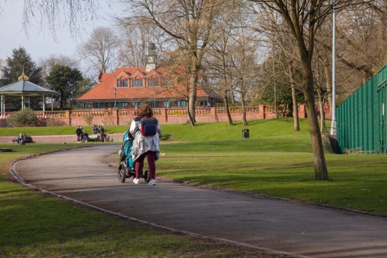 Parent pushing a baby stroller along a park path
