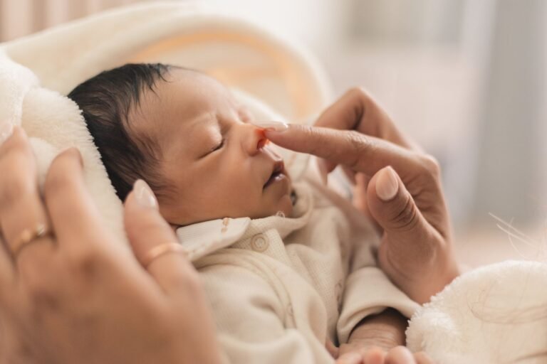 A parent gently caring for a newborn baby's nose — NoseFrida vs Frida Baby 3-in-1 Picker comparison