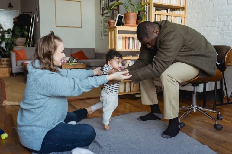 A parent helping a baby take first steps at home, the stage when a baby gate goes up