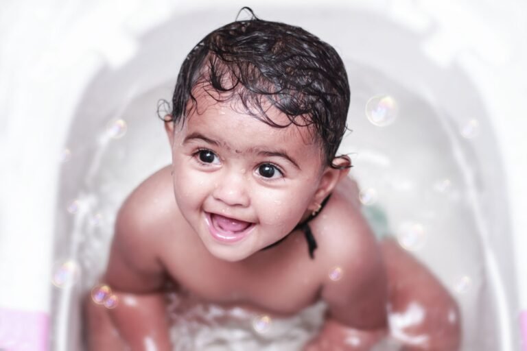 Baby smiling in a bath tub surrounded by bubbles