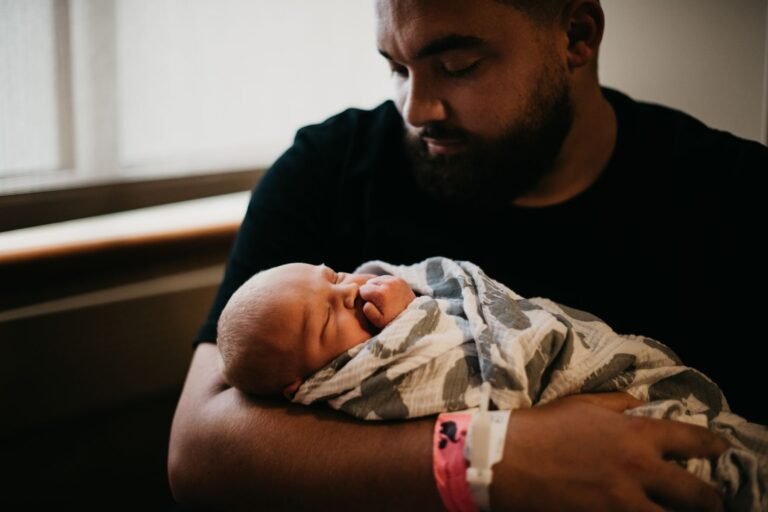 Parent holding a newborn wrapped close against their chest
