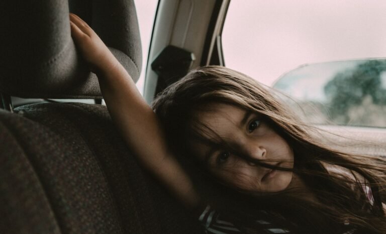 Child riding in the back seat of a car, looking out the window