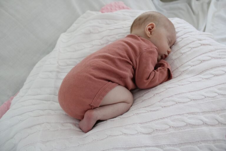 Baby sleeping peacefully on a knitted blanket at home