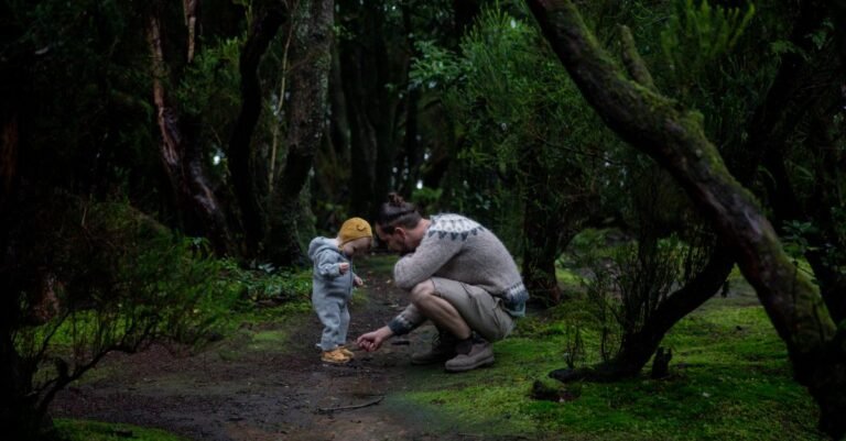 Parent hiking a mossy forest trail with a baby in a soft carrier