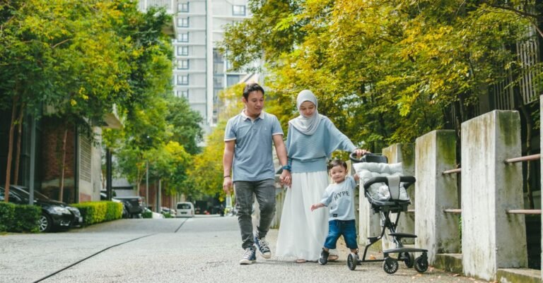 Family walking with a compact travel stroller in a city park